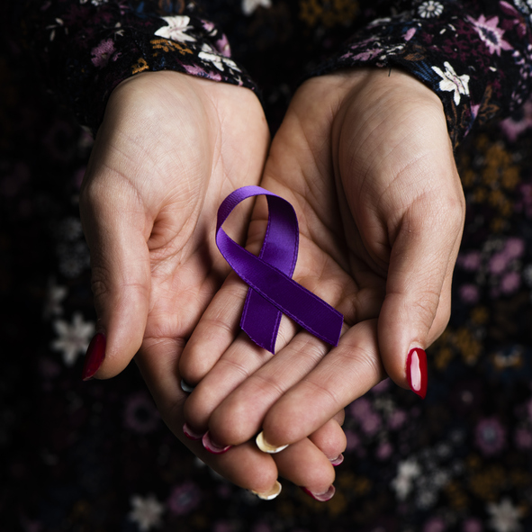 A woman holding a purple ribbon for domestic violence awareness month