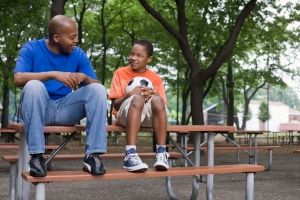 mentor and child sitting on bench with soccer ball