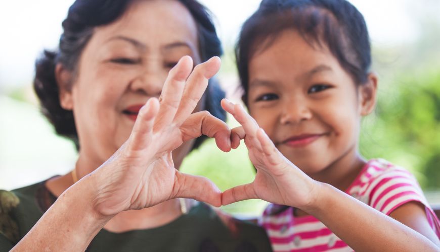 grandmother and grandaughter making a heart with their hands