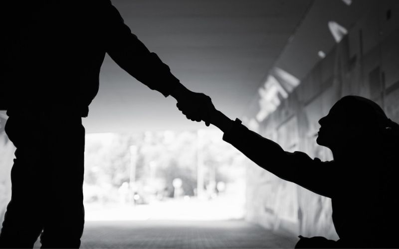 black and white image of a personenxtending a hand to help another person stand up