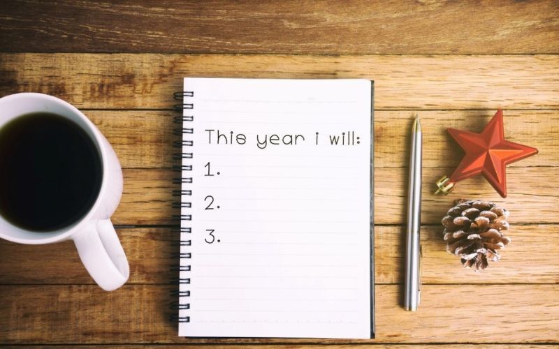 cup of coffee next to a list of new years resolutions to fill out