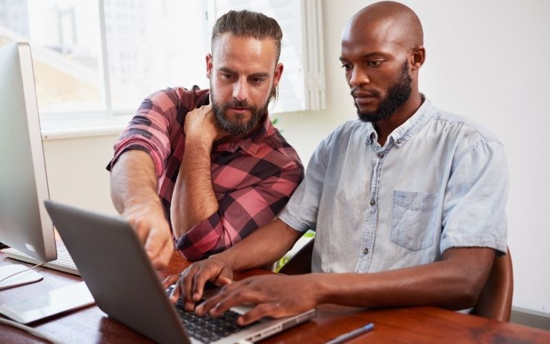 one man helping another at a laptop